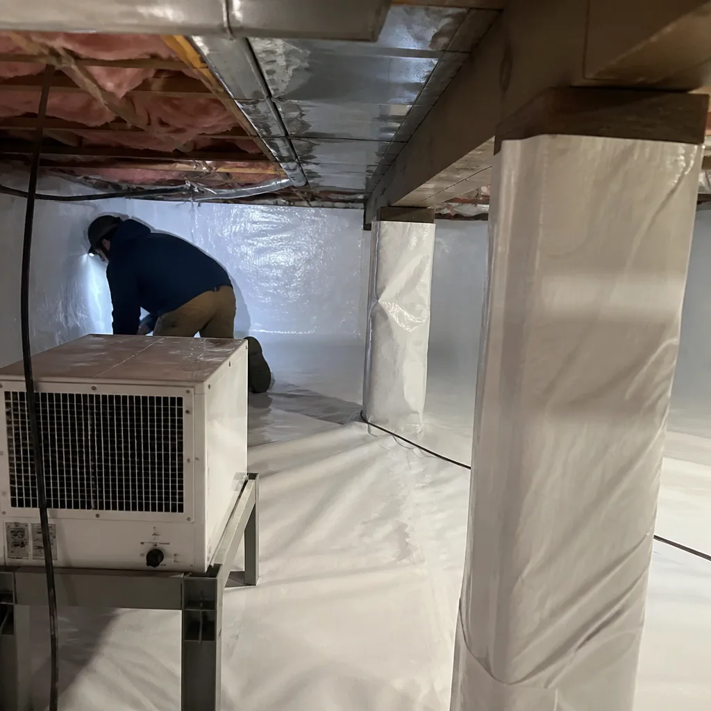 Technician performing professional crawl space encapsulation and vapor barrier installation